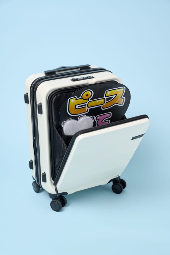 リップルプラスのスーツケースのフロントポケットをひらき、推し活用のうちわやペンライトを差した様子