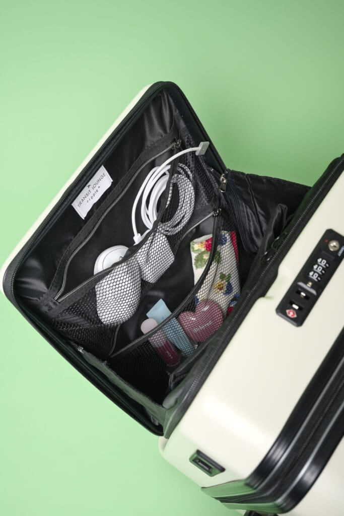 リップルプラスのスーツケースのフロントポケットを開け、充電器やマウスなどをネット型ポケットに入れた様子。