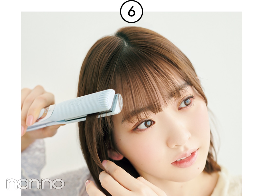 サイドの髪にストレートアイロンをかける女性