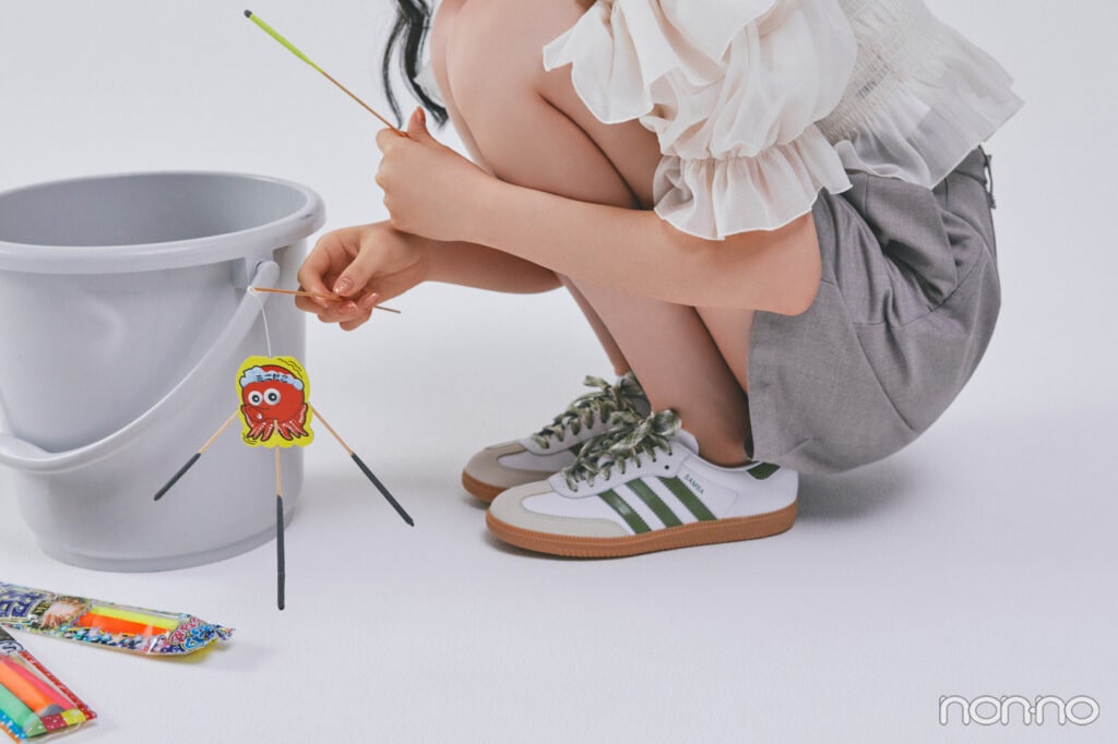 アディダスのスニーカーを履いてしゃがむ足元