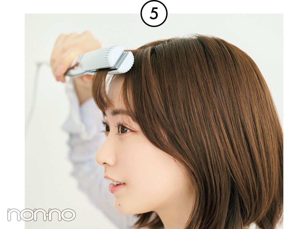 前髪全体をストレートアイロンではさむ女性