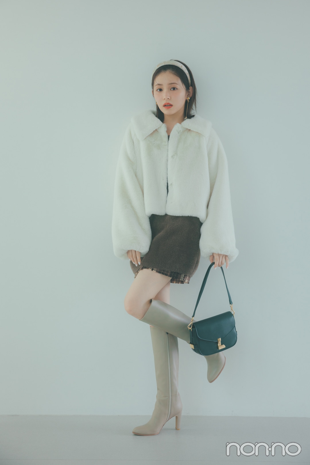 ロングブラウンニット×白アウター×ミニスカートコーデの女性