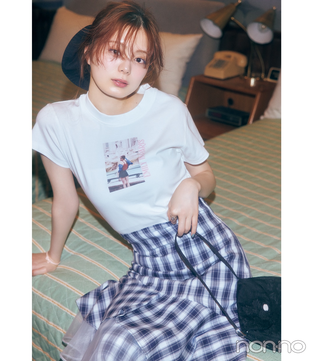 白のプリントTシャツ×チェック柄スカートコーデで座っている女性
