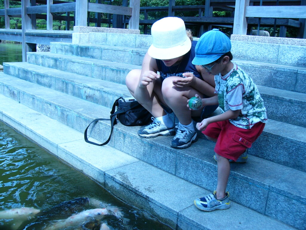 日本庭園で鯉に餌をあげる友野一希さん