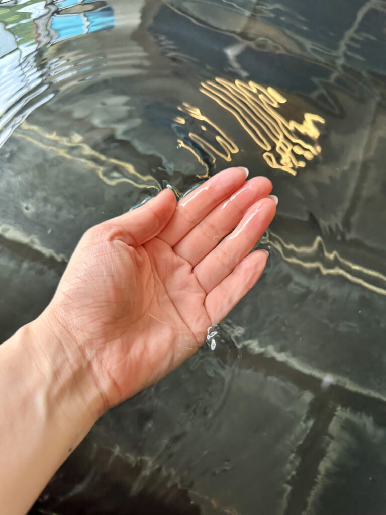 熊本県小国町　温泉　お湯を手ですくっている