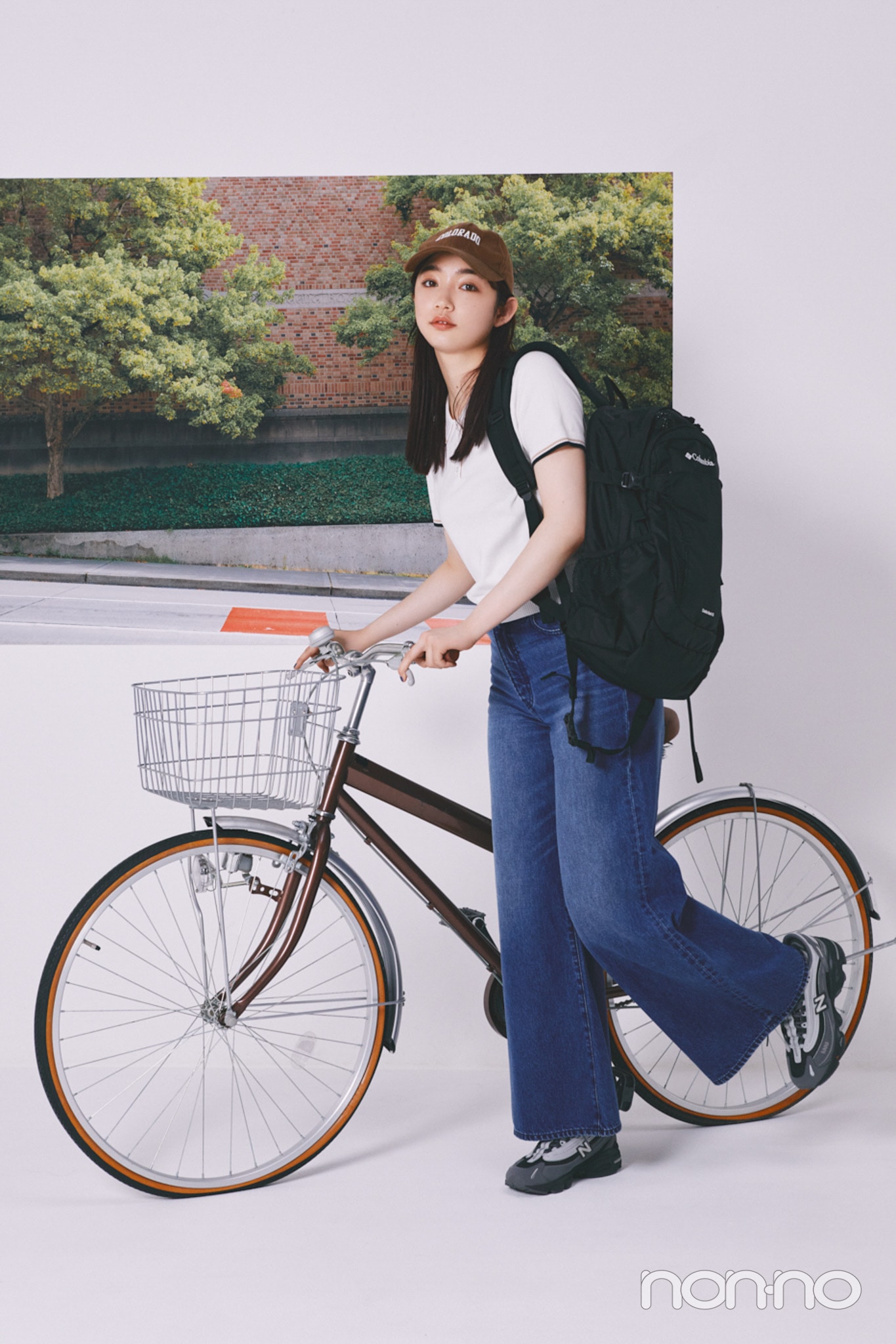 デニムにポロトップスを合わせ、自転車を押す小宮山莉渚