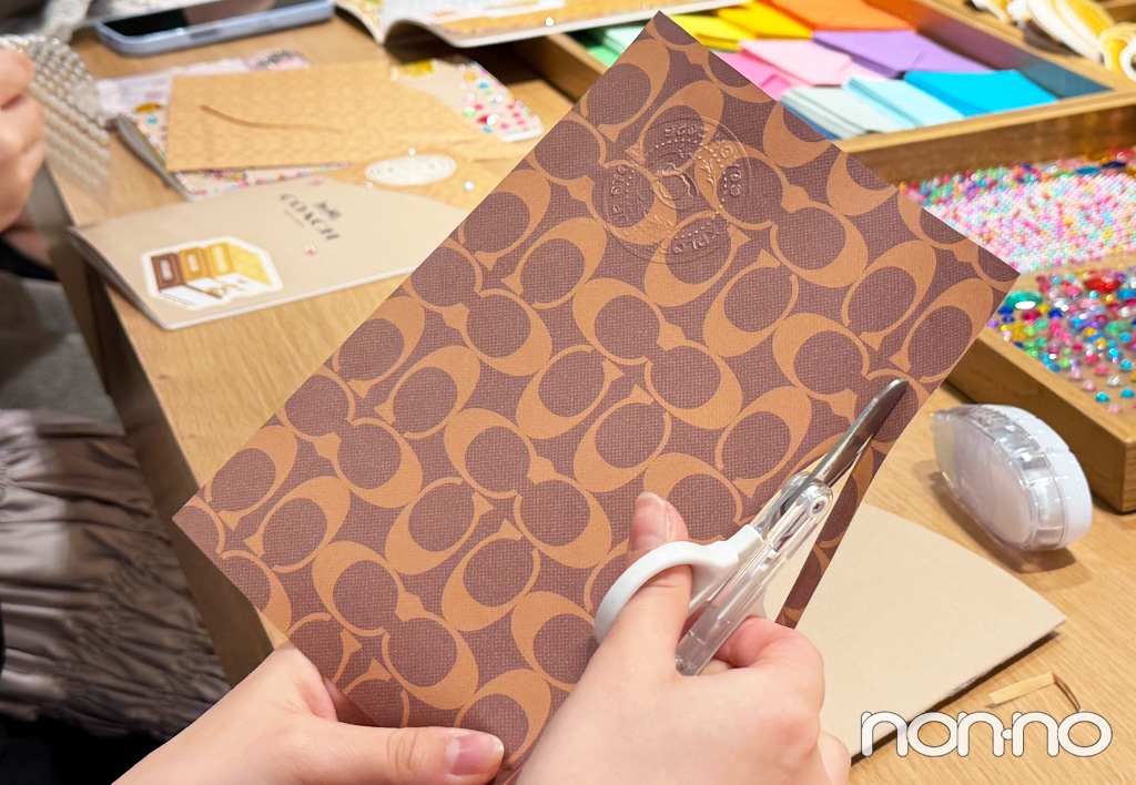 コーチのロゴがデザインされたペーパーをきる様子