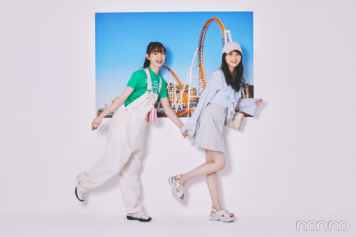 テーマパークの写真の前に立つ林芽亜里と小宮山莉渚