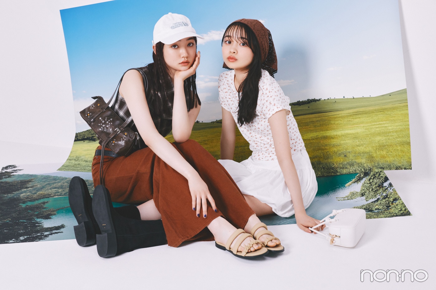 草原の写真の前に座る林芽亜里と小宮山莉渚