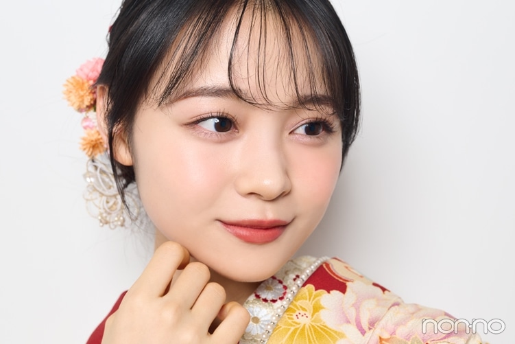 赤い着物を着て手に顔をあて横を向く林芽亜里