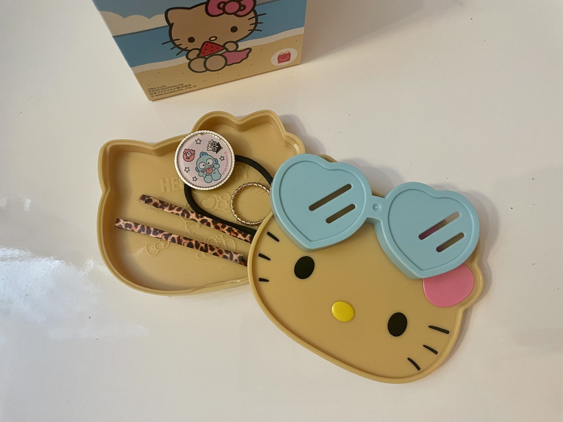 サングラスカップつきミニトレーにヘアピンやゴム、指輪などの小物を収納している