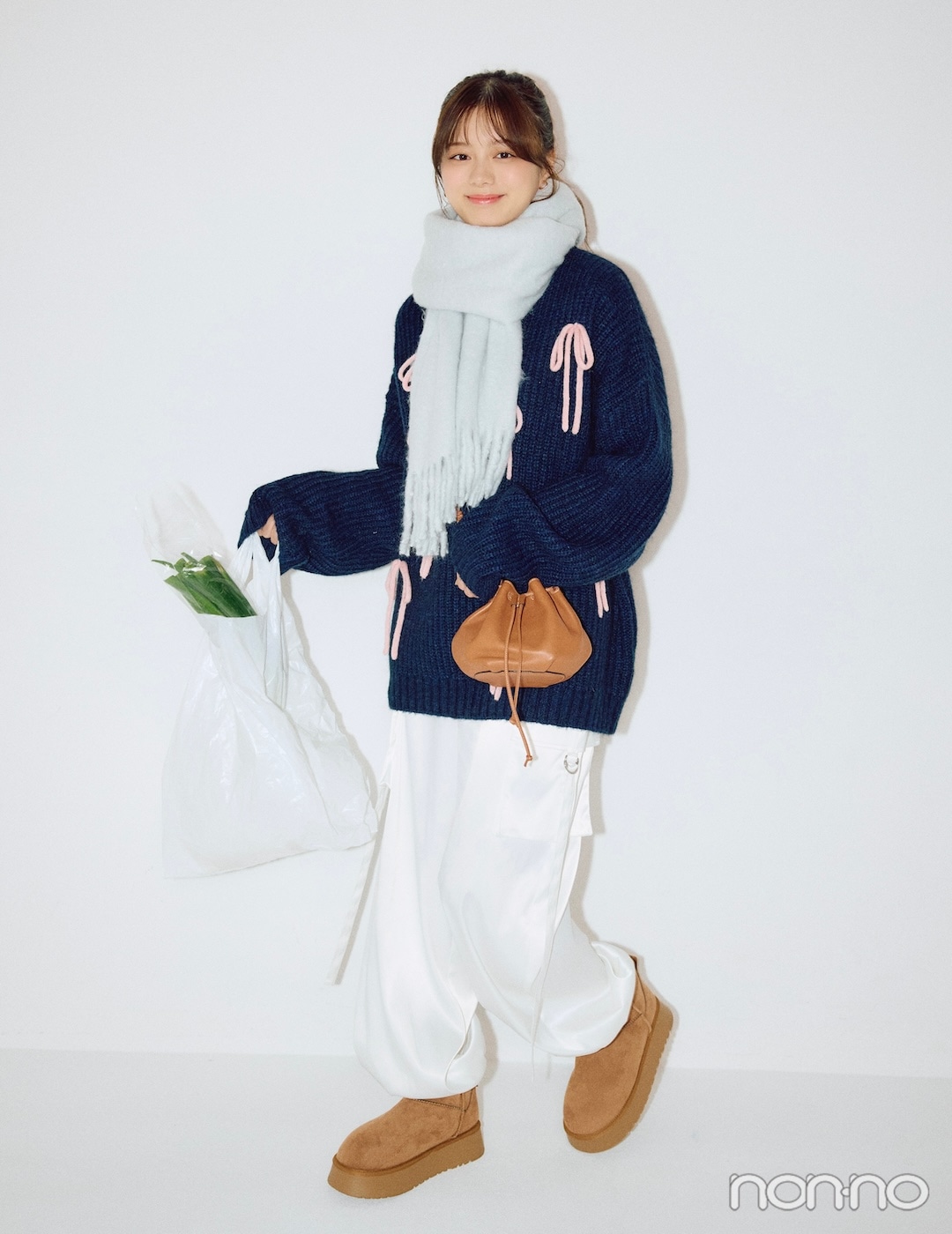 リボンのついたニットと白パンツを着た紺野彩夏