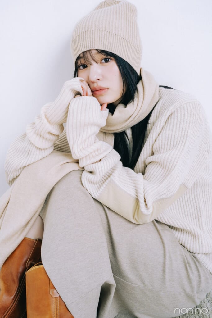 無印良品のメリノウールイブ編みアームウォーマーをつけ、淡色コーデで仕上げて座っている横田真悠