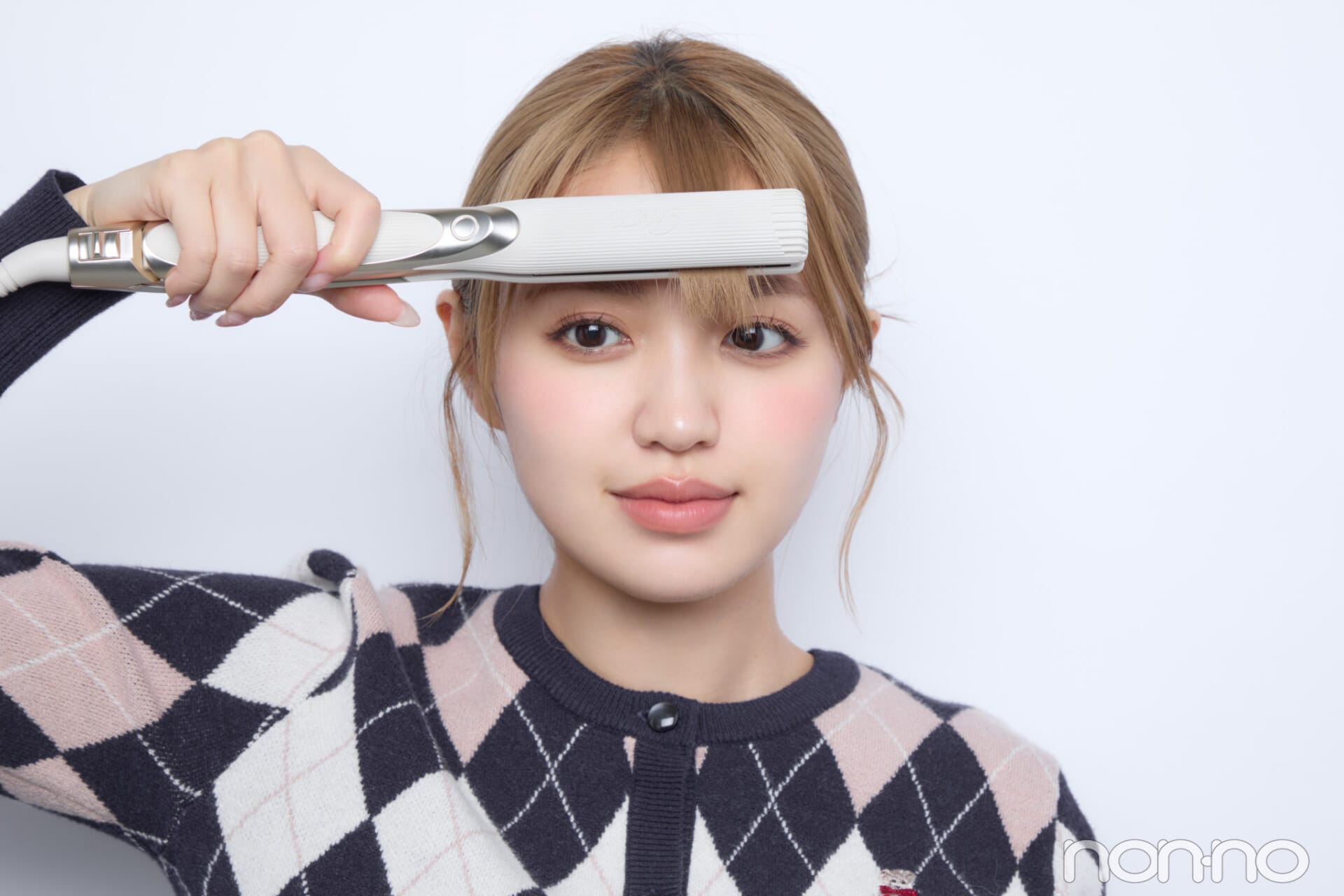 ストレートアイロンで前髪をはさんでいる女性