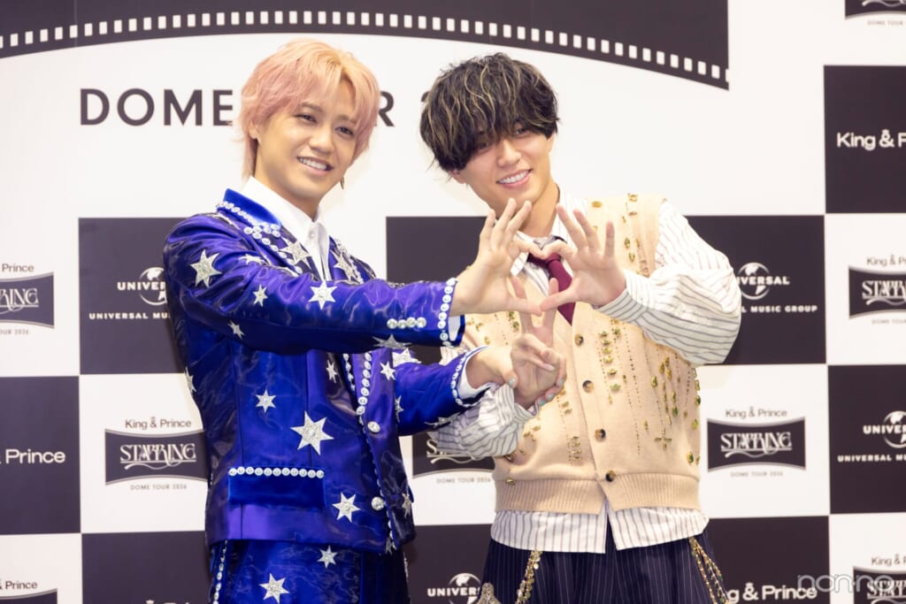 二人で作った♡の後ろからピースをする永瀬廉さんと、その手首をぎゅっとつかむ髙橋海人さん