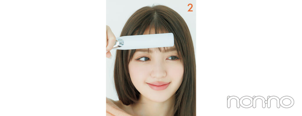 ストレートアイロンに前髪をはさんでいる女性