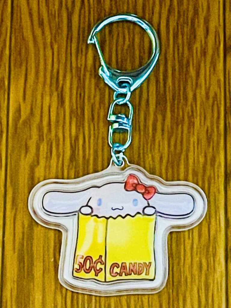 シナモンのキーホルダー。キティ展のロゴにちなんで、黄色い紙袋から顔を出すデザインとなっている。