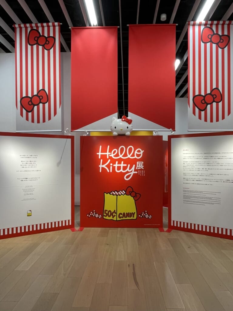 ハローキティ展の最初のブース。キティ展のロゴと歴史が記載された看板が3つ並んでいる。