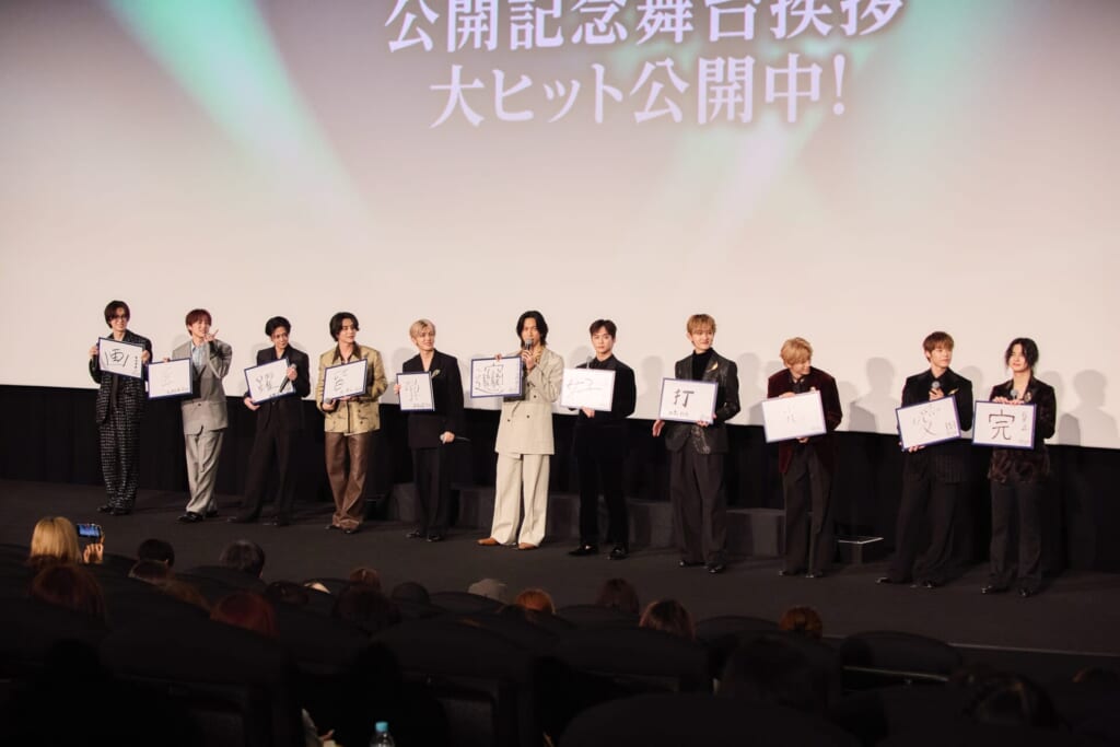 漢字一文字を書いたフリップを見せるINIメンバー