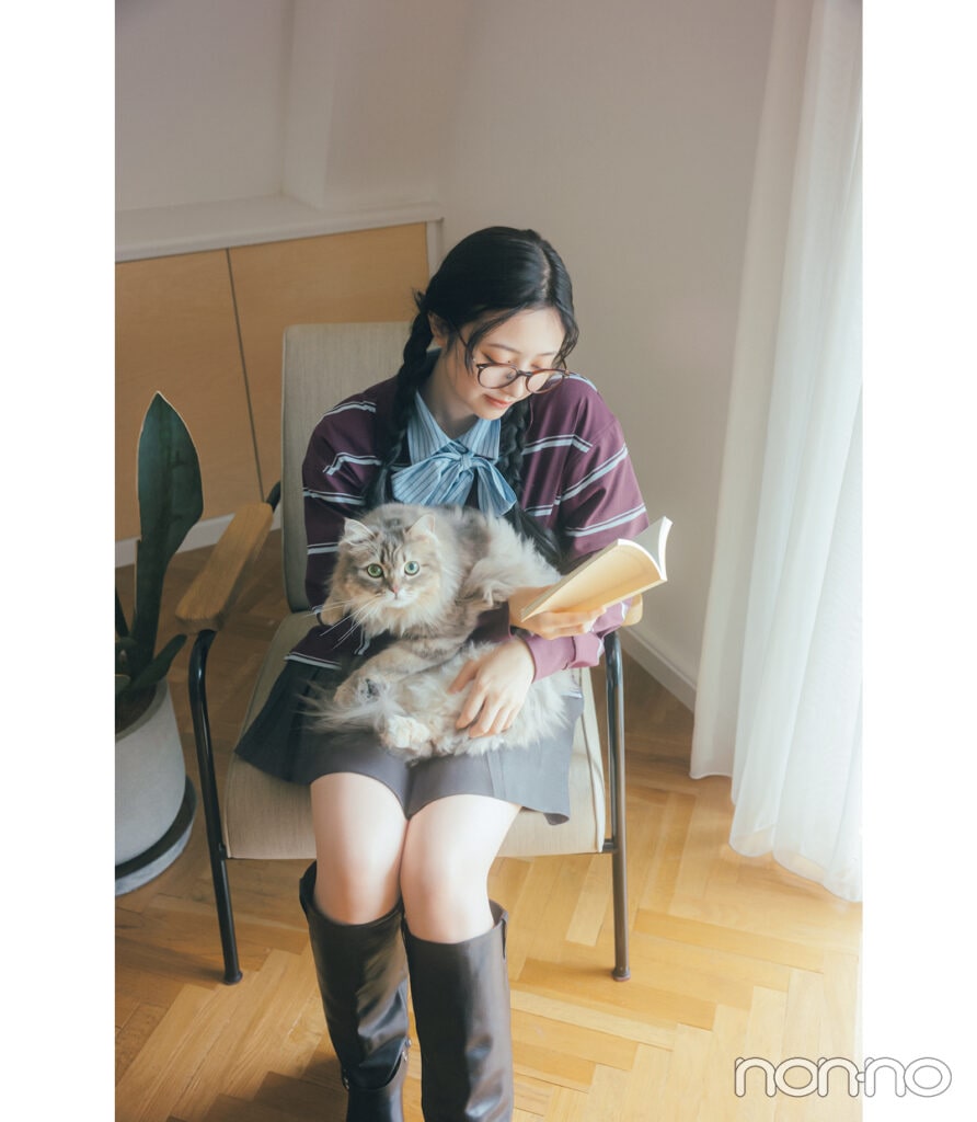 猫を膝に抱きながら本を読む井上和