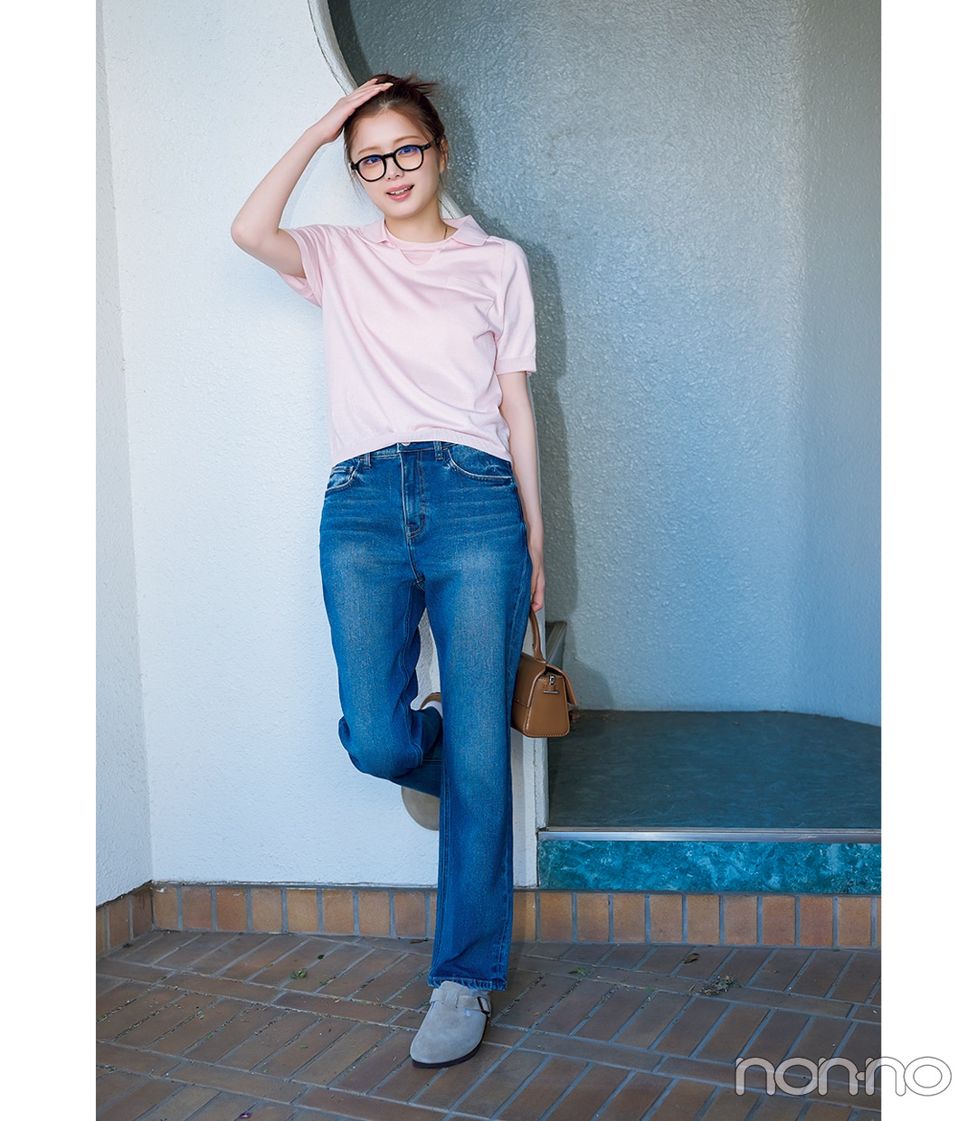 ピンクカラーTシャツ×デニムパンツコーデでミニバッグを持っている女性
