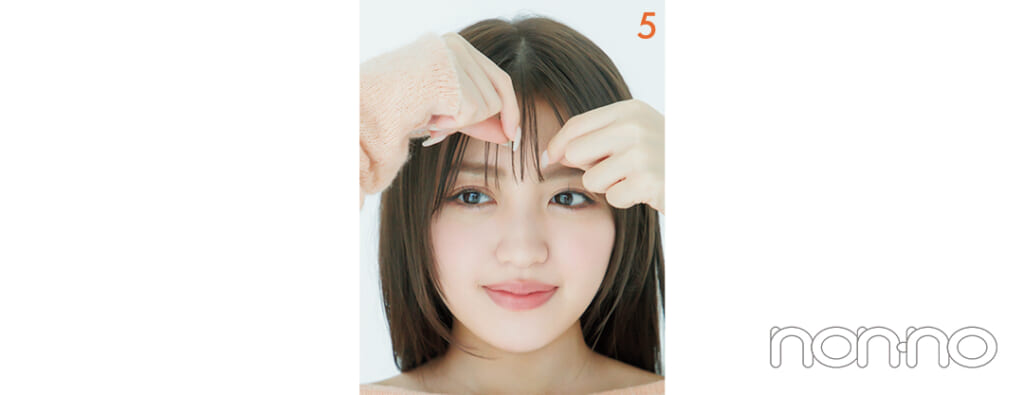 前髪を指でつまんでいる女性