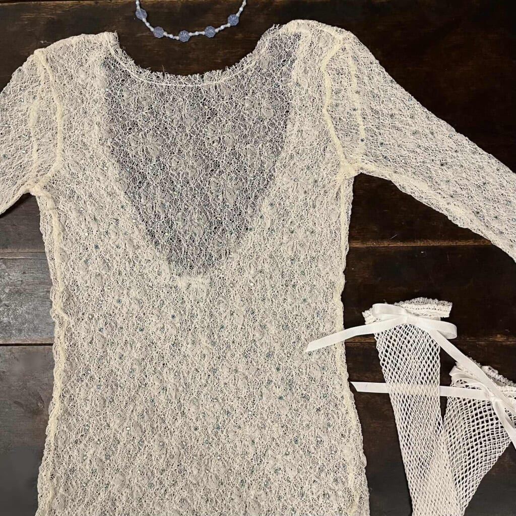 ラインストーンがついたレースシャツ 青いビーズのネックレス 白いリボンの靴下 が並んでいる