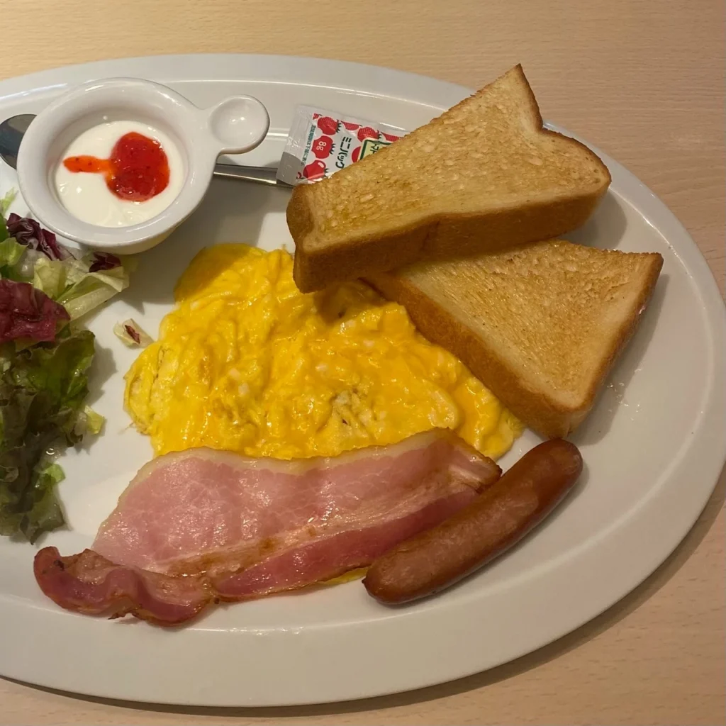 食パン、スクランブルエッグ、ベーコンなどのモーニングプレート