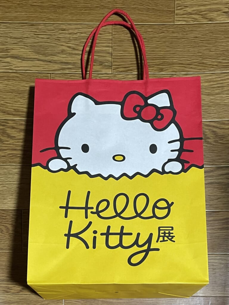 キティ展限定の紙袋。黄色い紙袋からキティが顔を出しているデザイン。