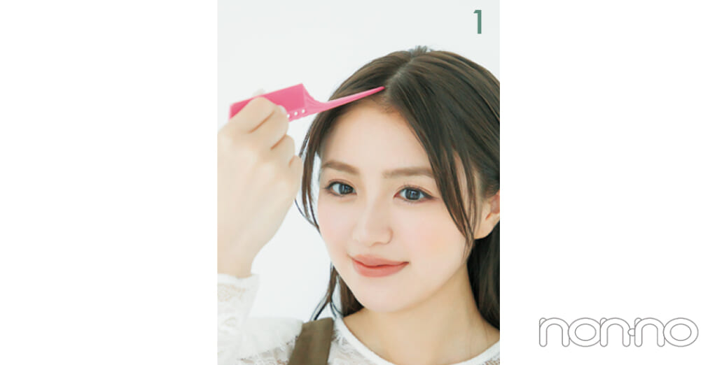 コームの柄の先を前髪にあてる女性