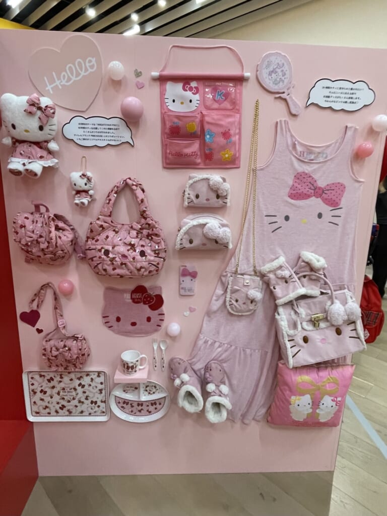 ピンク色をモチーフとしたキティのグッズがピンク色の壁に飾られている。バッグやポーチ、スリッパなど多様だ。