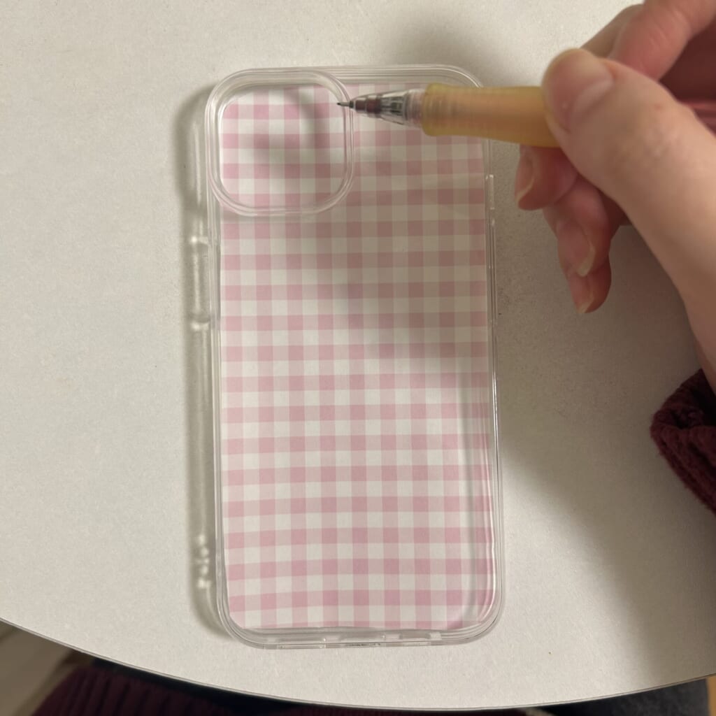 折り紙をスマホケースでかぶせて、型取りをしている写真。