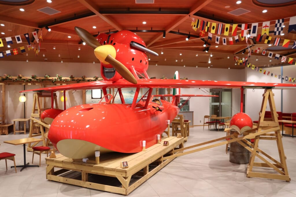 愛・地球博記念公園の北口エントランス近くにある「ロタンダ 風ヶ丘」のカフェテリア内観。2025年11月1日にリニューアルし、『紅の豚』に登場する飛行艇「サボイアS-21」が展示され、提供メニューが和食から洋食に変更