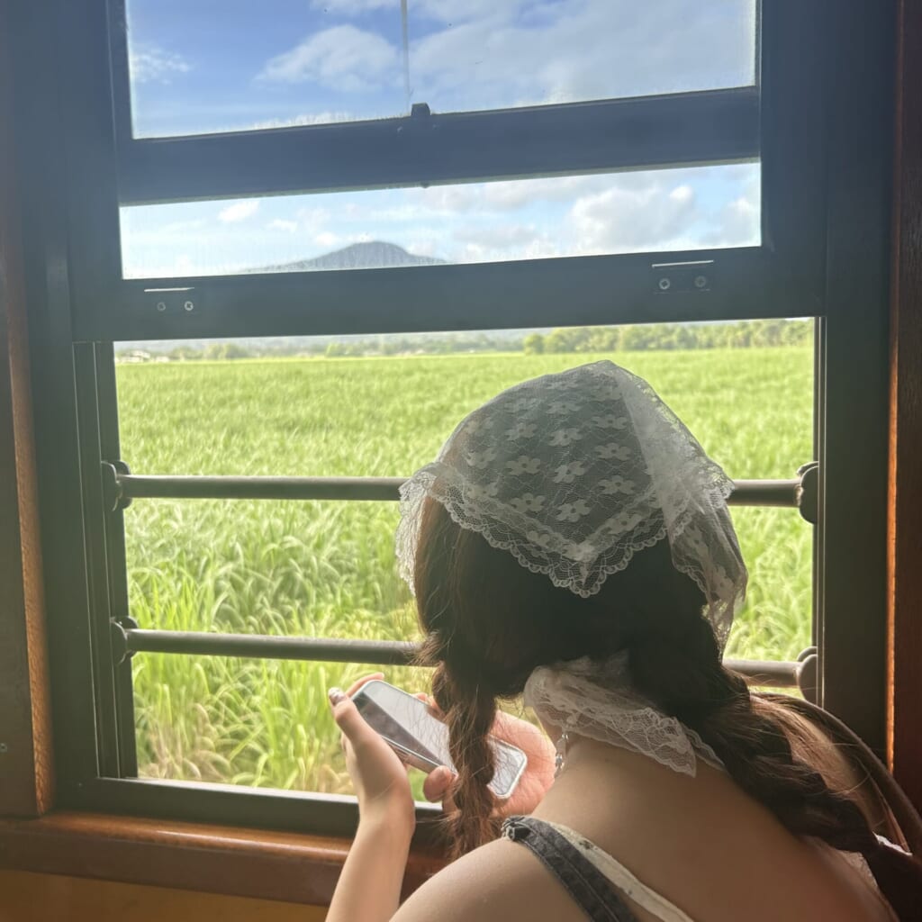 列車の窓から女の子が外を見ている写真。