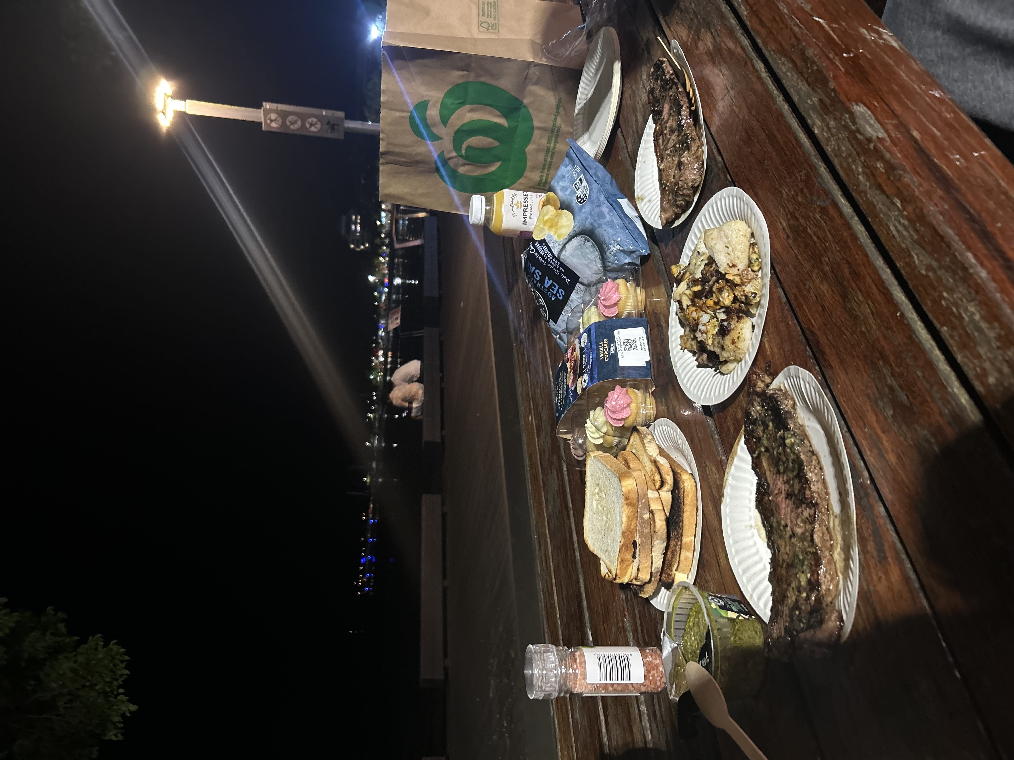 ビーチの前のベンチに料理を広げて食べる写真。