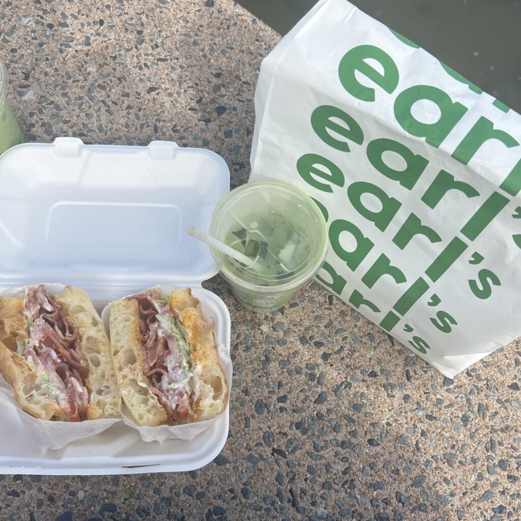 ベーコン、レタス、トマトがサンドされたフォカッチャと抹茶ラテの写真。