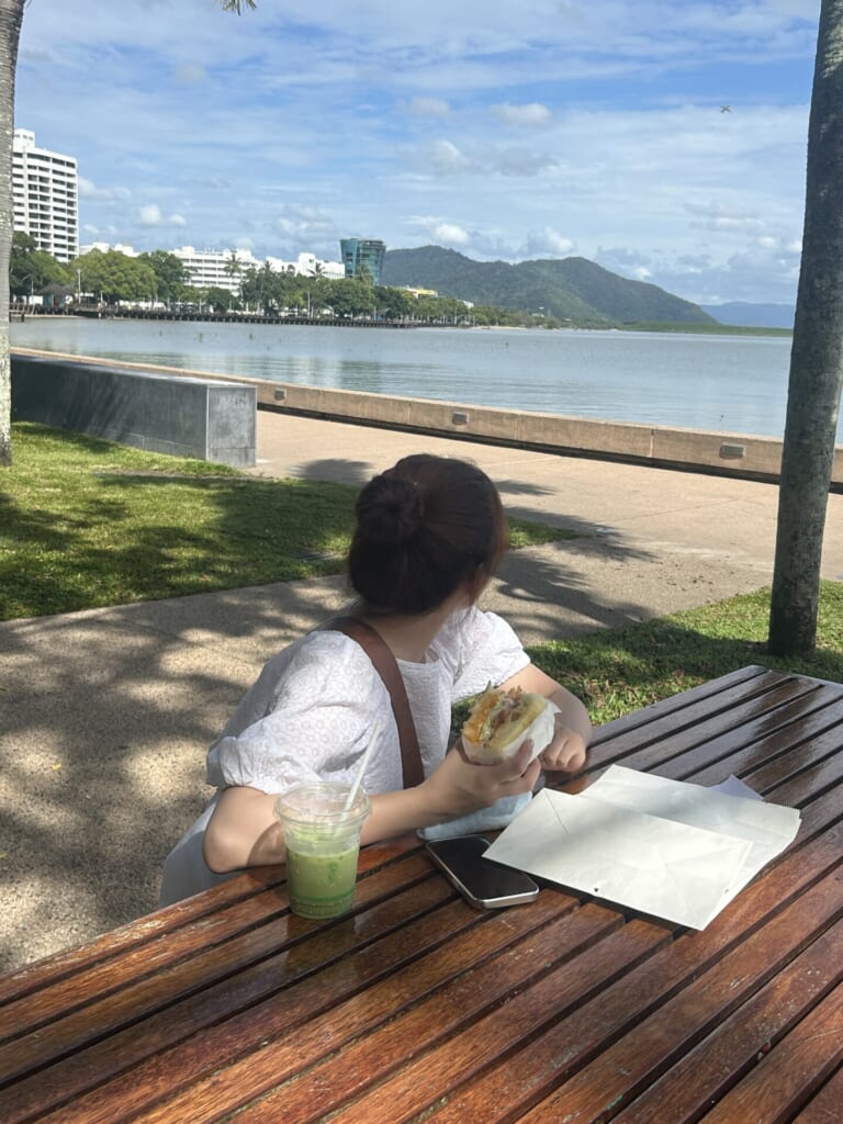 ビーチ近くの机でサンドを食べている写真。