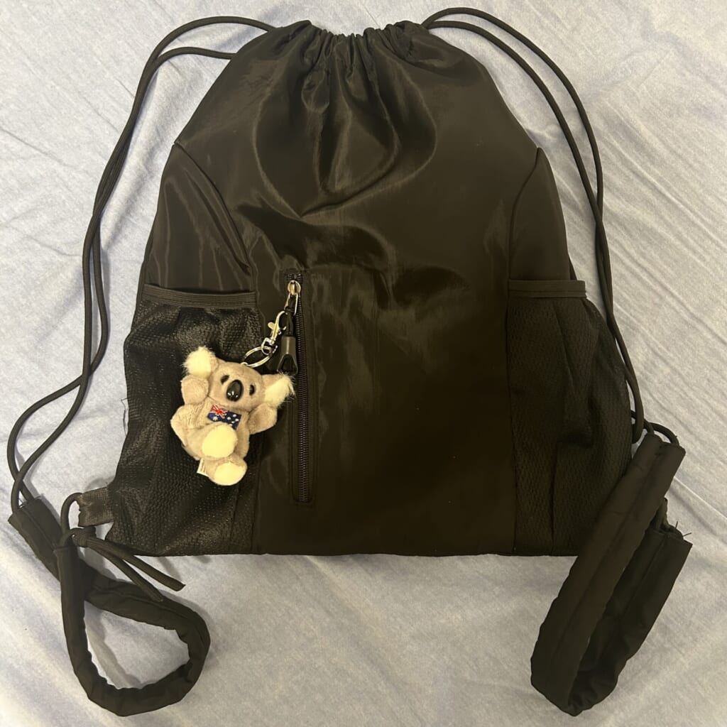 ナップサックの写真。コアラのキーホルダーをチャックに着けている。