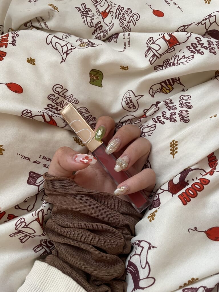 グロスを持ってネイルを見せている