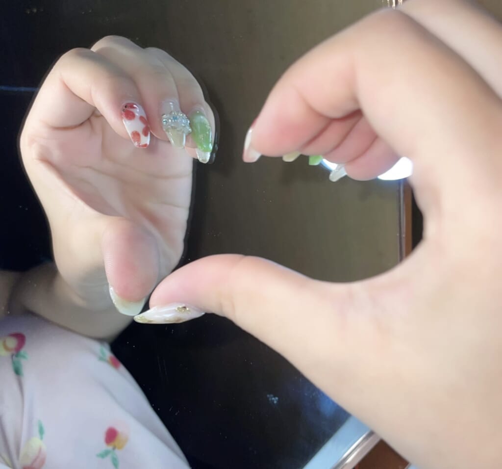 片手でハートの半分を作って、鏡に当ててハートの形にしている。