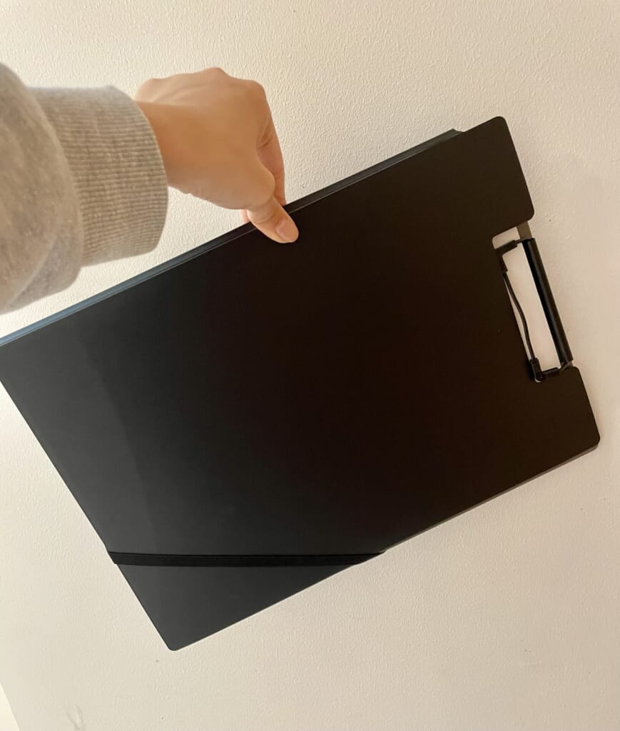 書類をはさんだままクリップホルダーを横に傾けている