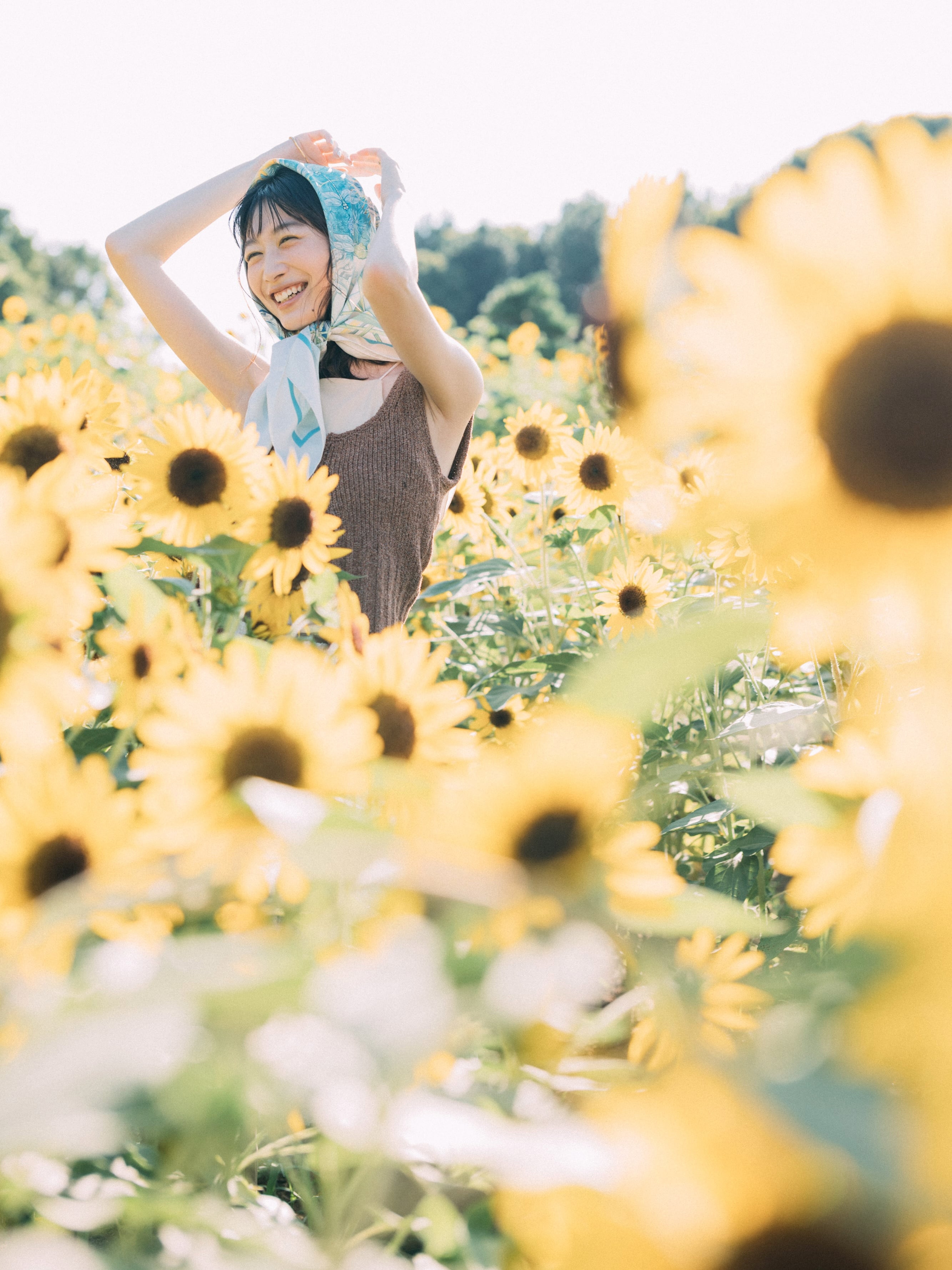 ヒマワリ畑で両手を上げて笑っている岡本夏美