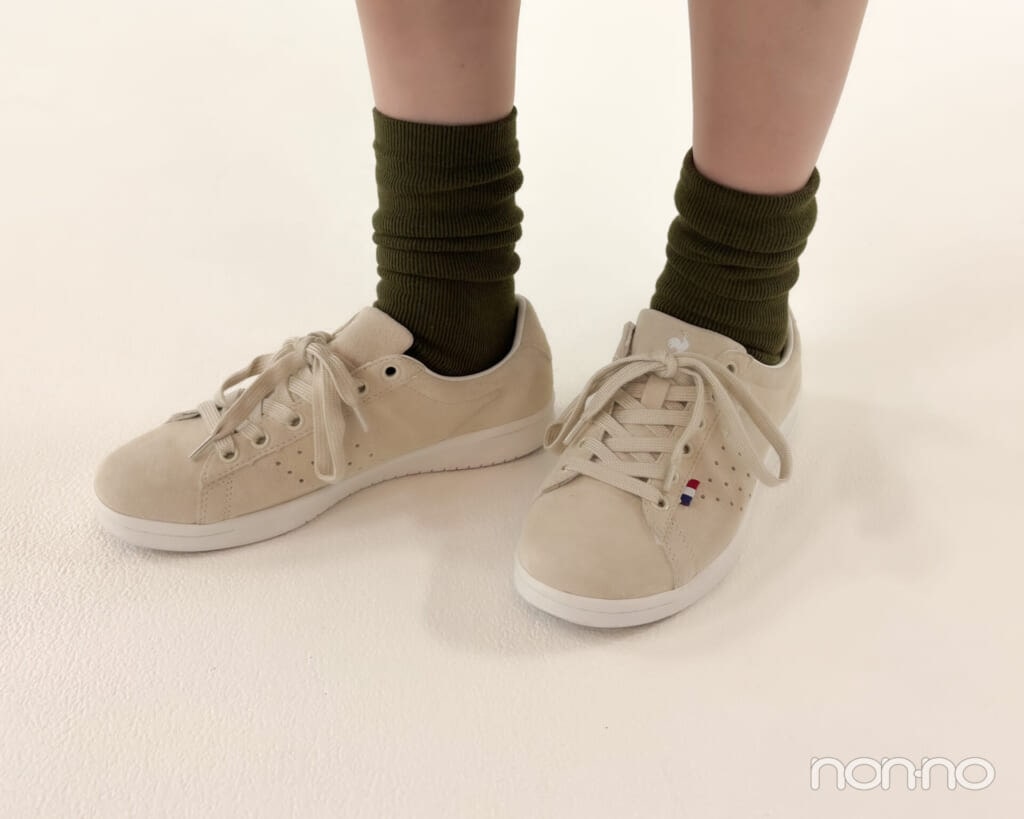 ベージュのスニーカーとカーキの靴下を履いた足元