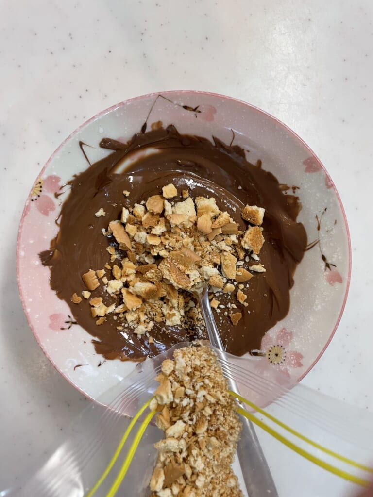 溶かしたチョコに砕いたクッキーを混ぜている