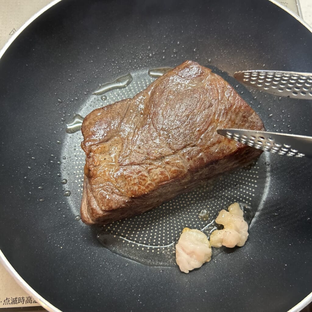 高温のフライパンで牛脂を使い塊肉の表面を焼き付ける工程