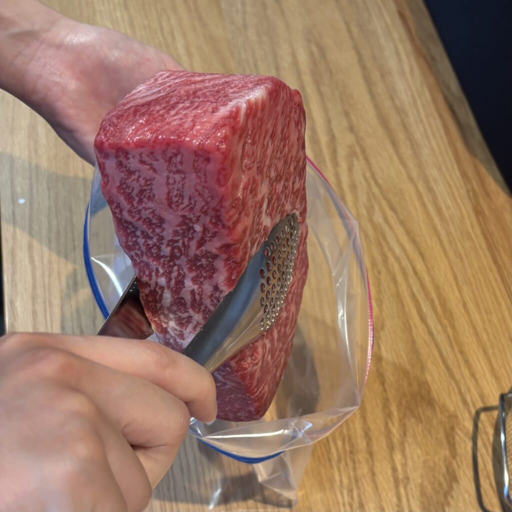 空気を抜きながら牛の塊肉を保存袋に入れる下準備