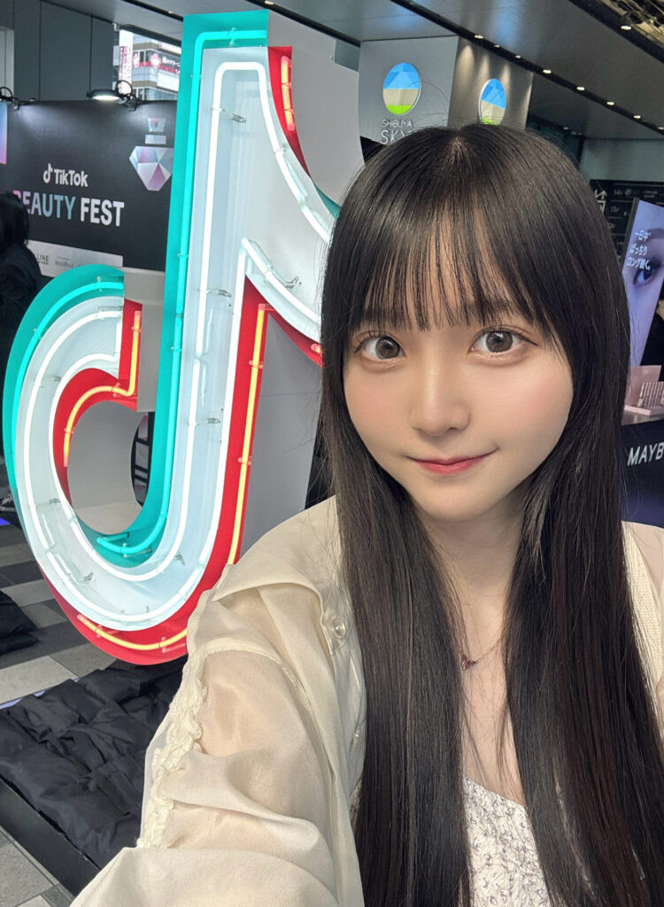 TikTokのロゴモニュメントの前で自撮りする小杉怜子