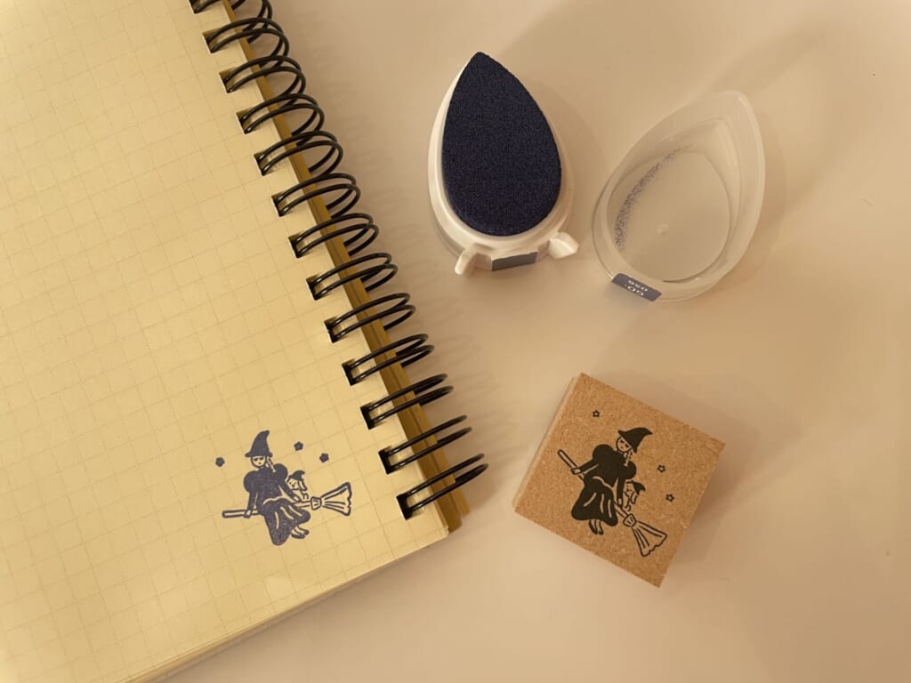 魔女のスタンプとスタンプ台を使ってノートにスタンプを押している