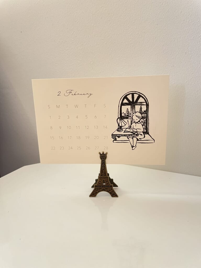 エッフェル塔クリップにカレンダーを挟んでデスクに置いてある
