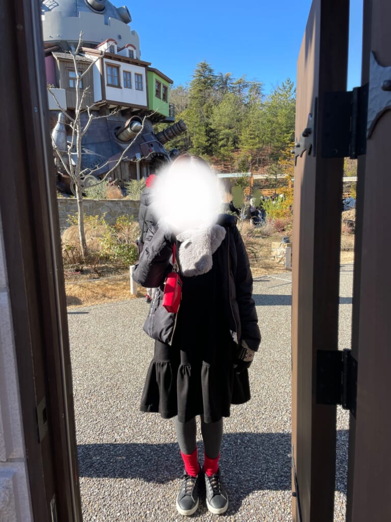 黒いダウン、黒いミニ丈ワンピース、グレーのタイツ、赤い靴下のコーデ